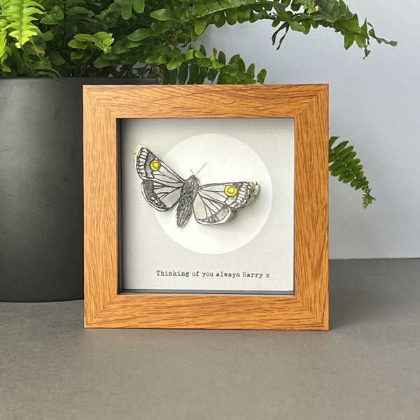 Moth artwork in dark wood effect frame displayed on shelf with book page wings and soft moon detail